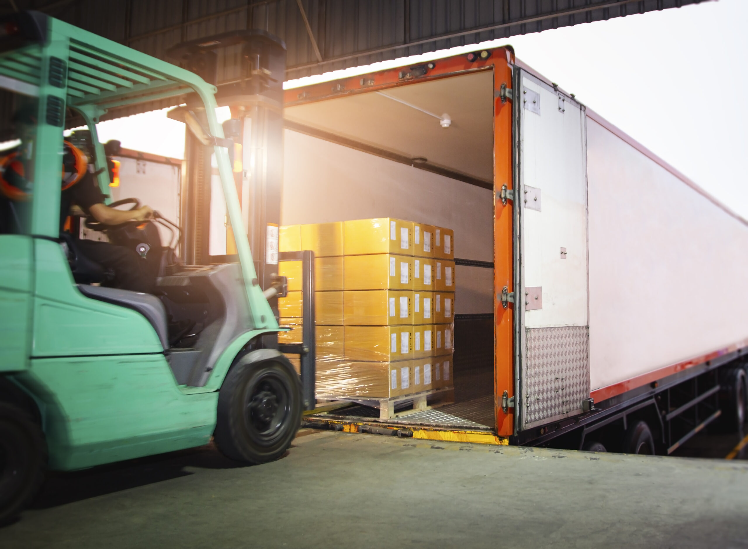 a forklift moves a stack of boxes into the back of a tractor trailer